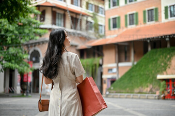 A beautiful Asian woman walking on the street, strolling in the beautiful city alone