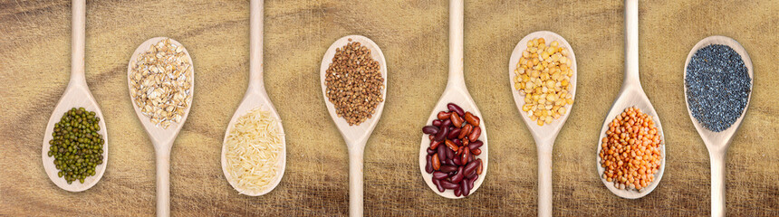set of wooden spoons filled with various seeds on a scratched wooden background