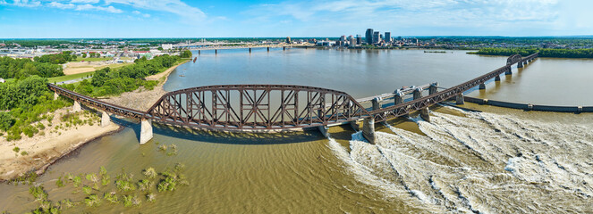 Panoramic railroad bridge next to Ohio River dam distant bridges and Louisville KY aerial