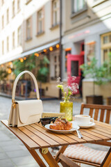 handbag with glasses, croissant with coffee on the table