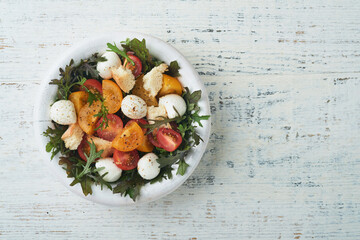 Tuscan Panzanella. Cherry Tomatoes salad with arugula, basil, mozzarella and bread crackers on white bowl. Traditional italian salad. Mediterranean healthy food and cuisine.