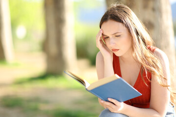 Worried woman reading a paper book in nature