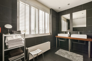 a modern bathroom with black tile walls and white trim around the tub, sink, mirror, and towel rack