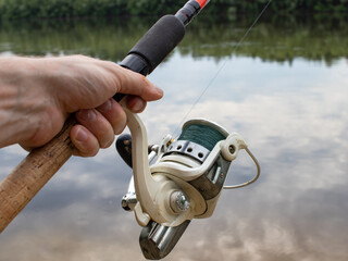 fishing rods in a man's hand on the background of a river with nature
