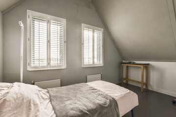 a bed in a room with white shutters on the windows and a small table next to it that is empty