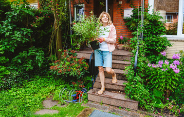 Smiling mature woman moving down on steps with plant