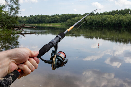 fishing rods in a man's hand on the background of a river with nature
