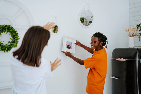 Boyfriend showing picture frame placing on wall at home