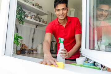 Man cleaning kitchen window sill at home