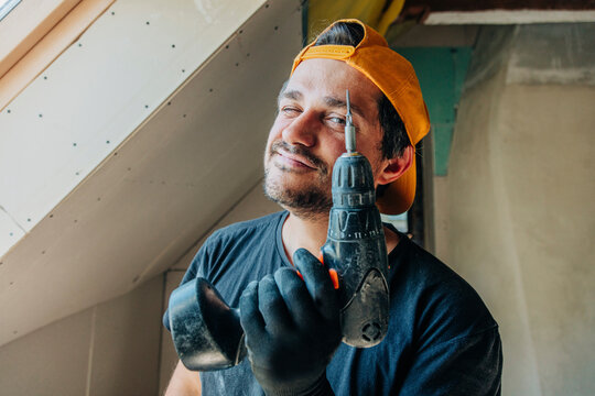 Smiling man winking and holding drill in attic