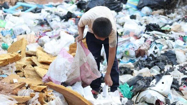 A poor boy collecting garbage waste from a landfill site in the outskirts . children work at these sites to earn their livelihood. Poverty concept.