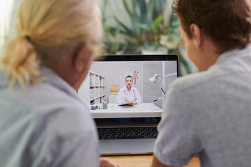 .Senior man and his son having online meeting with general practitioner