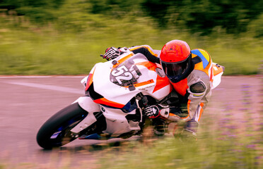 A motorcycle racer is driving fast on a motorcycle track.