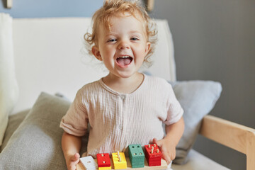Toddler's imaginative play. Montessori learning tools. Laughing blonde little blonde baby girl...
