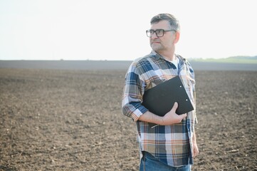 The farmer works on the ground. Male farmer on a plowed field, planting cereals in the spring in the ground. Agricultural business concept. Growing food, vegetables.