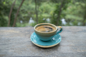 Fototapeta na wymiar Blue cup of coffee with nature green background
