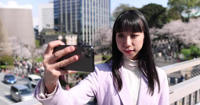 A portrait of selfie by Japanese woman behind cherry blossom 