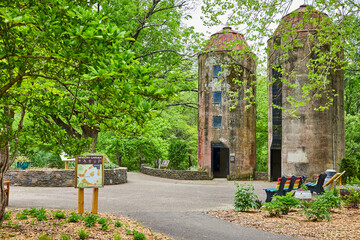 Sensory Garden sign leading to two old silos with pride benches along trail in summer
