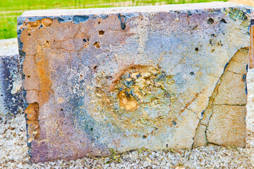 Explosion blasted concrete block with chemical bursts of color and embedded glass shards