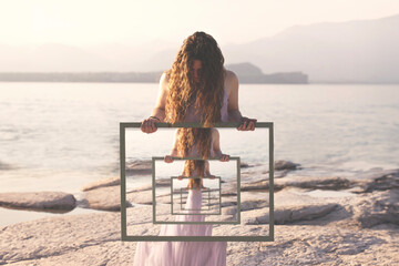 woman holding a surreal frame with the reflection of herself in loops, abstract concept - 626813821