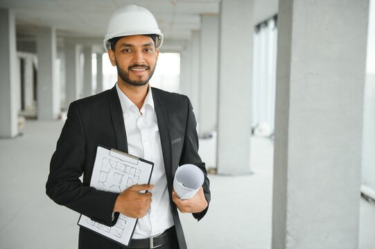 Asian engineer handsome man or architect with white safety helmet in construction site. Standing at modern building construction. Worker asian man working project building