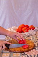 Persona cortando tomates en una tabla de cortar encima de una encimera rústica de azulejo