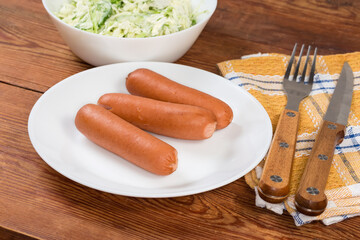 Serving of the steamed Vienna sausages with green vegetable salad