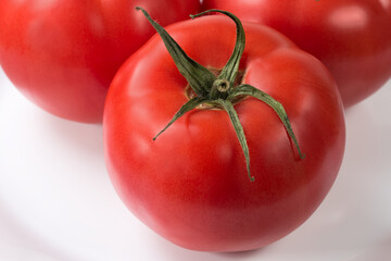 Pink tomatoes on white dish, close-up in selective focus