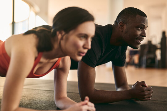 Young athletes doing plank exercise at fitness club