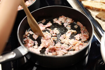 frying bacon in small pieces in a frying pan