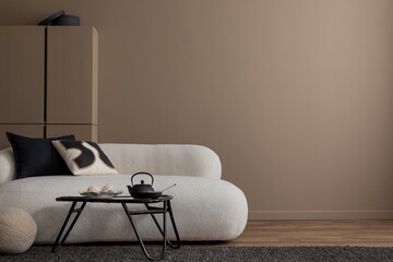 Minimalist composition of warm living room interior with copy space, white boucle sofa, gray plaid, beige pillow, wooden coffee table, brown shelf, and personal accessories. Home decor. Template.