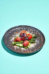Salad with baked asparagus and tomatoes in a plate on a blue background