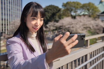 A portrait of selfie by Japanese woman behind cherry blossom bust shot