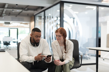 In a modern office African American young businessman and his businesswoman colleague, with her striking orange hair, engage in collaborative problem-solving sessions