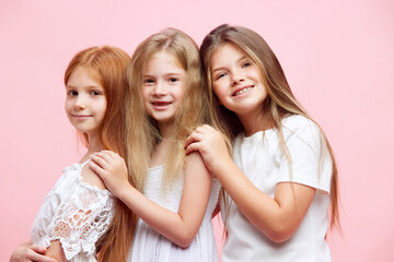 Beautiful little girls, sisters, children posing with smile against pink studio background. Concept of skincare, childhood, cosmetology and health, beauty, organic products, ad