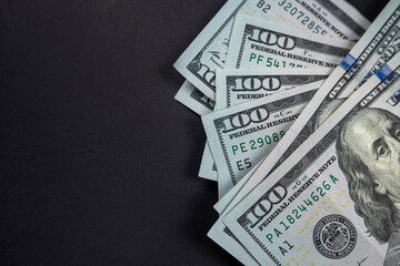 Close-up stack of hundred dollar bills isolated on black background.