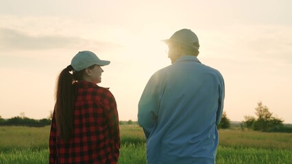 agriculture industry, two farmers work green field at sunset, field wheat, growing green plants, senior agronomist talks about work modern farming, commercial activities, financial investments - obrazy, fototapety, plakaty