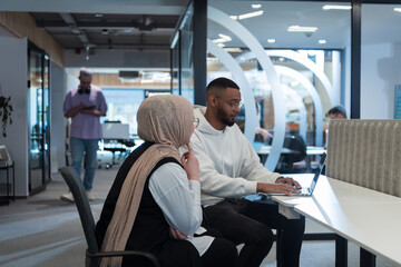 In a modern office setting, an African American businessman and his Muslim colleague, wearing a...