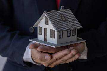 Mortgage concept. Small toy house in business man hand buy or sell real estate Financial agent complete Home sales and home insurance concept, 