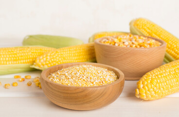 Corn groats and seeds with fresh cobs on wooden table