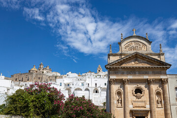 OSTUNI, ITALY, JULY 12, 2022 - Landscape of Ostuni with the church Maria Santissima of Carmine in foreground, Province of Brindisi, Puglia, Italy