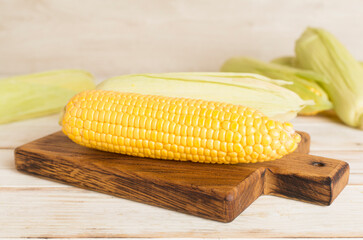 Fresh corn on cobs on wooden table