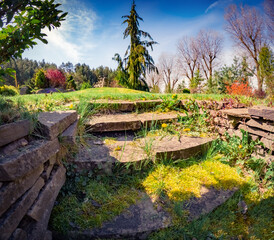 Stone staircase in garden. Sunny spring scene of shore of lake. Amazing view of first warm day in city park. Beauty of nature concept background.