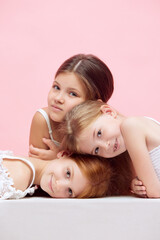 Obraz na płótnie Canvas Portrait of little beautiful children, girls posing together against pink studio background. Well-being. Concept of skincare, childhood, cosmetology and health, beauty, organic products, ad