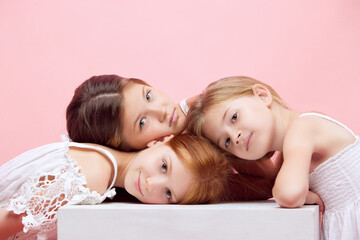 Portrait of little beautiful children, girls posing together against pink studio background. Well-being. Concept of skincare, childhood, cosmetology and health, beauty, organic products, ad
