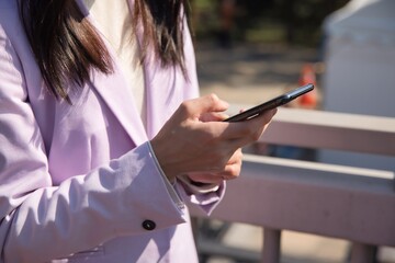 Body parts of hands using smartphne by Japanese woman at the street