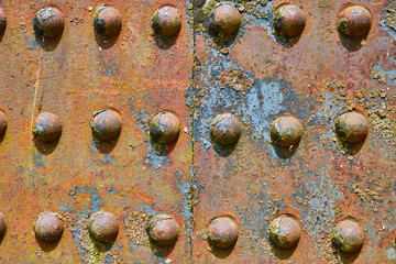Background asset colorful rivets on industry iron metal corroding with flaking yellow rusty decay