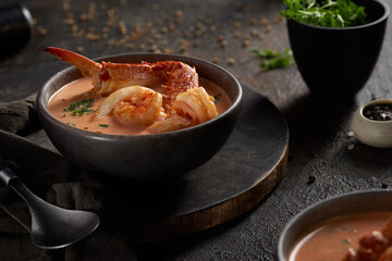 A closeup of a seafood soup black bowl
