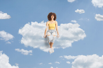 Obraz premium Young caucasian female with afro hairstyle sitting on a cloud