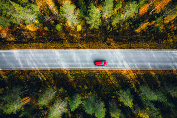 Aerial view of red car on a country road in forest in Finland